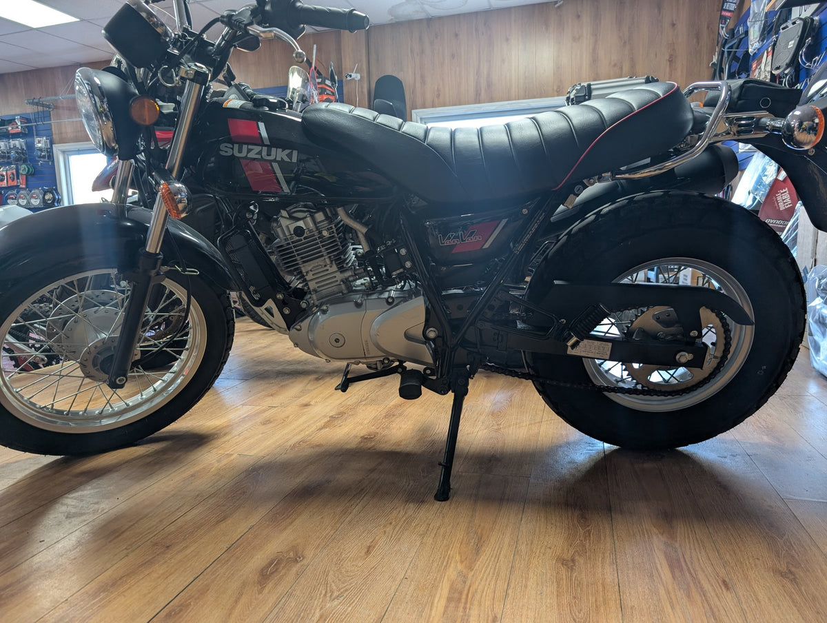 Black 2018 Suzuki VanVan 200, right side profile, inside the Garage Harry Stanley showroom